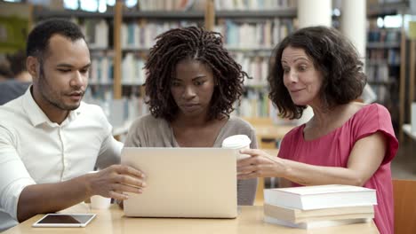 Colegas-Pensativos-Sentados-En-La-Biblioteca-Y-Comunicándose