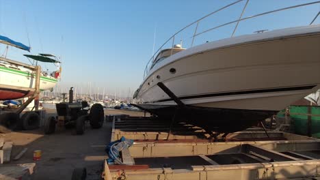 superyacht parked on a metal cradle out of the water on a slipway in a boat yard with an anchor on the bow surrounded by yachts