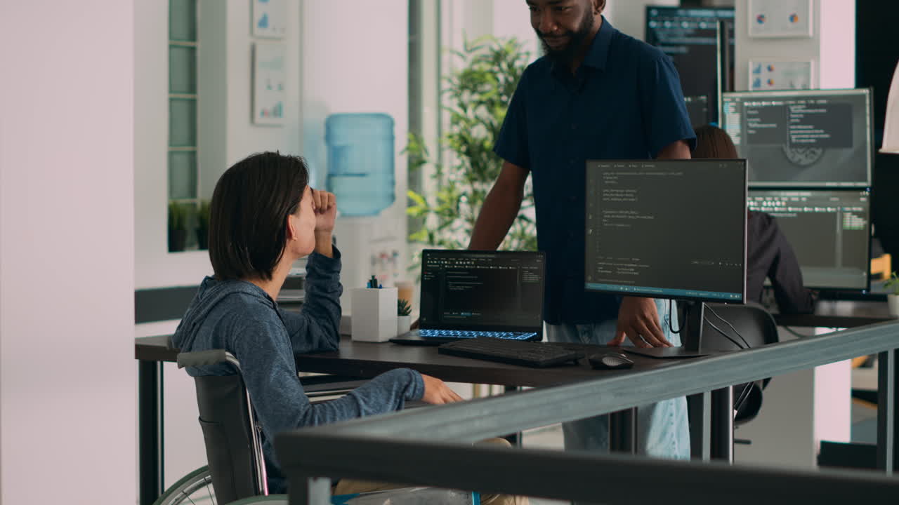 App developer talking to coder with chronic impairment in server room office