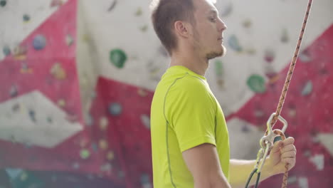 man belaying another climber on an indoor climbing wall. a man using insurance climbers holds the rope and insures his partner who climbs the mountain