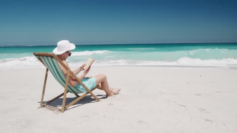 man reading a book on the beach