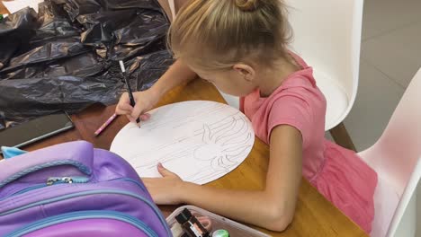 girl drawing a spider on a circular piece of paper