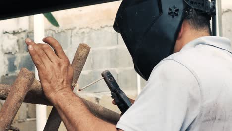 soldador profissional que emprega uma máquina de solda industrial para unir duas peças de metal criando uma estrutura metálica como parte de seu trabalho diário em uma pequena empresa local