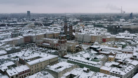 snow-covered old town (krakow city center - main square, sukiennice - cloth hall and town hall) at cloudy morning, krakow, poland