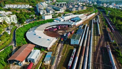 aerial footage of a railway depot, featuring a roundhouse with locomotives and rail cars on surrounding tracks