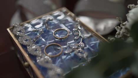 close up of wedding rings and sparkling bridal jewelry displayed in a glass box