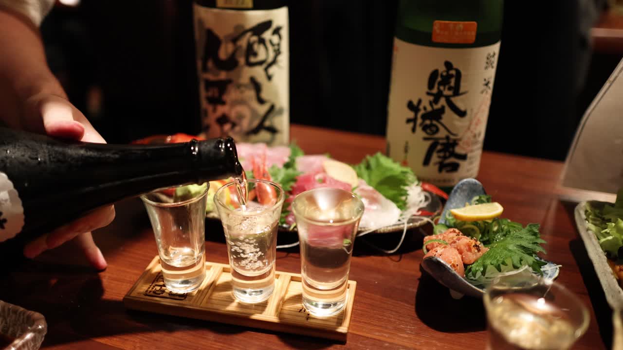 Sequential sake pouring into glasses with garnishes