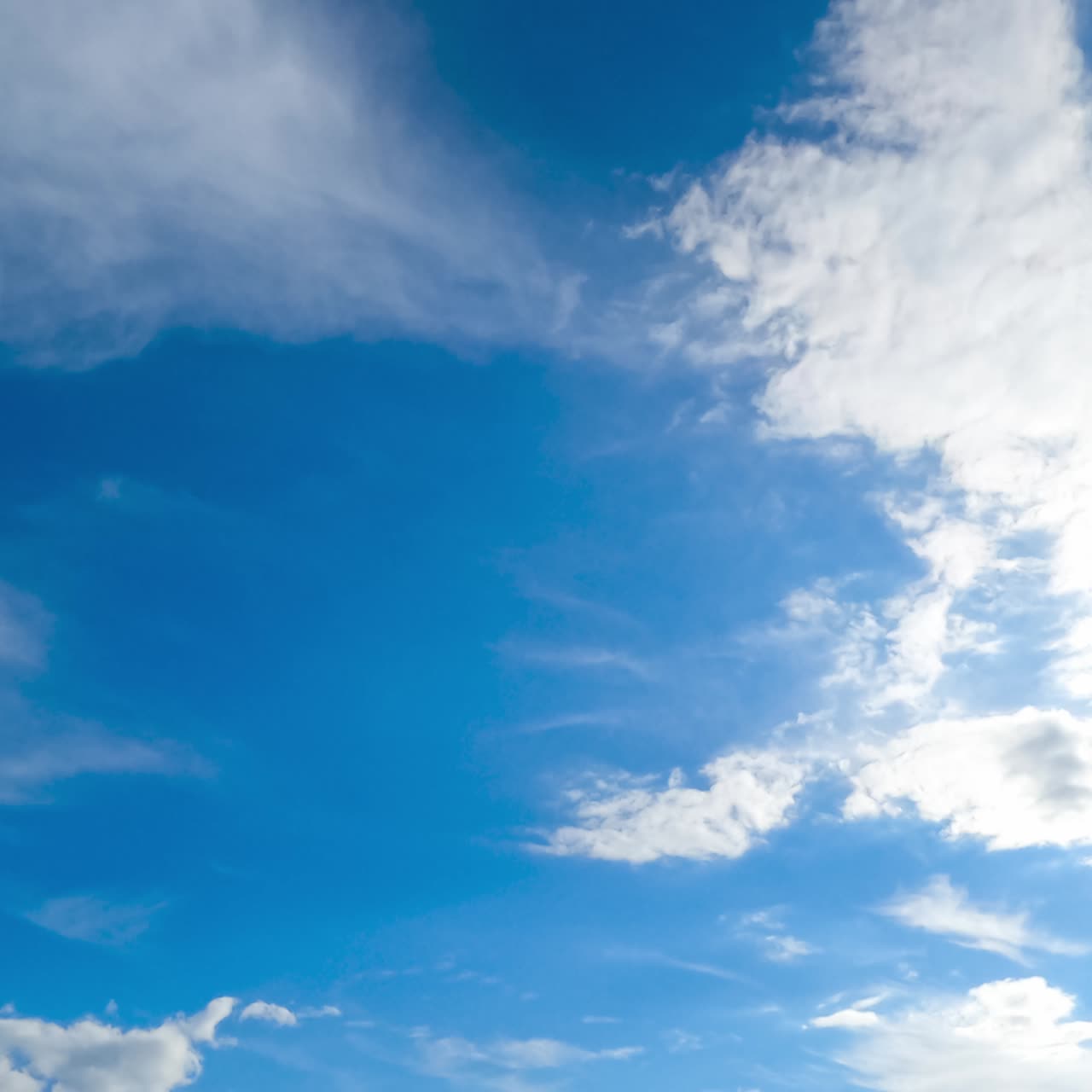 Soft light white clouds moving in different directions. Spindrift clouds lit with bright sun. Timelapse