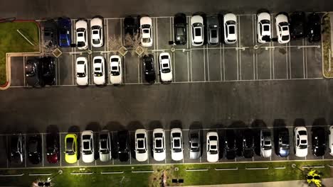 straight down rising aerial view of a car dealership parking lot at nighttime