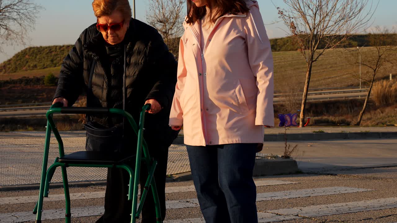 Pregnant woman helping elderly lady cross street with walker, sunny afternoon mood
