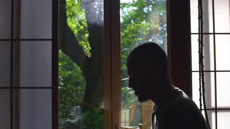 silhouette side view of adult male sitting and meditating indoors