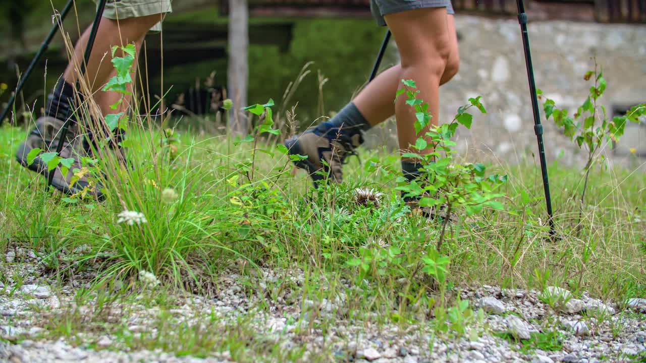 low angle view of legs of a couple, hike shoes, and trekking poles. Slow motion