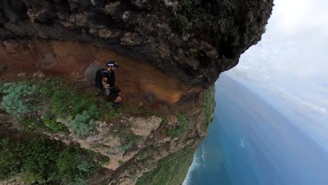 selfie shot of a young and fit man running down the trail on the side of a steep mountain at quebrada do negro in madeira