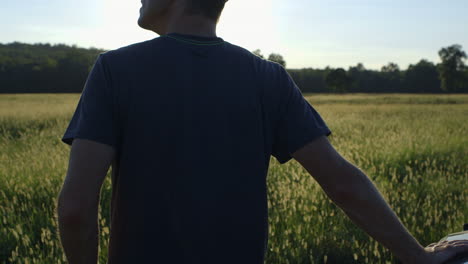 A-pro-photographer-gazes-out-at-a-beautiful-sunset-and-a-golden-field-of-grain-and-grasses-then-checks-his-time-lapse-camera