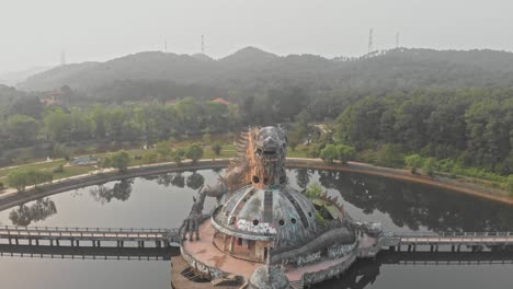 flying backwards at giant dragon creature old abandoned water park hue, aerial