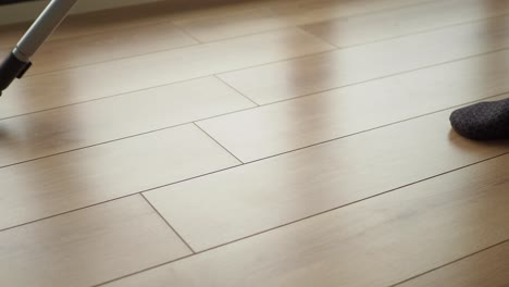 a person vacuuming a hardwood floor in their living room.