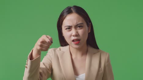 close up of angry asian business woman scolding while standing on green screen in the studio