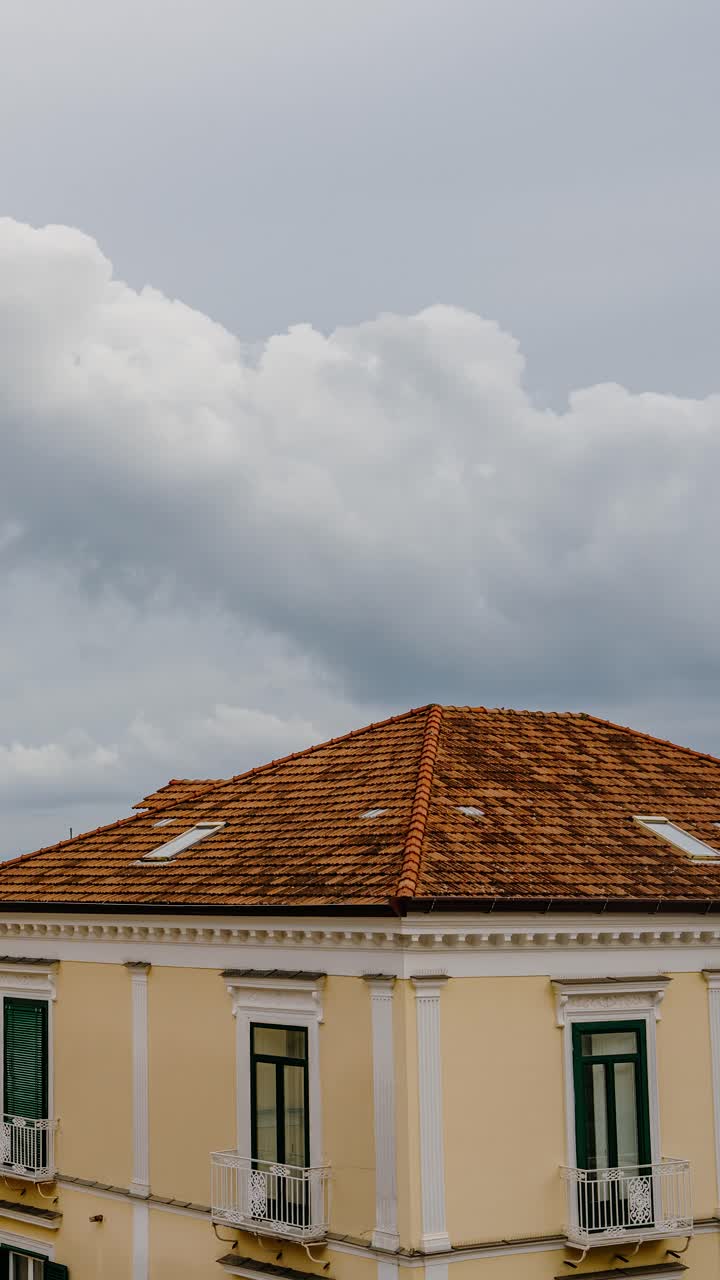 Timelapse verticale per reel di viaggio: Tetti di Amalfi sotto un cielo molto nuvoloso. Architettura storica e atmosfera costiera italiana in una giornata estiva nuvolosa.