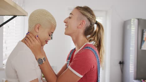 feliz pareja de mujeres diversas abrazándose y besándose juntos en la cocina