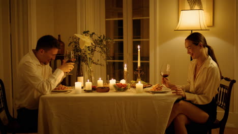 los recién casados riendo bebiendo copas de vino en casa, los amantes alegres divirtiéndose.