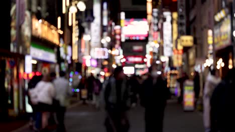 time-lapse of pedestrians in a neon-lit street at night.