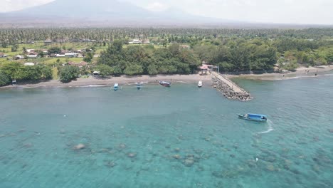 4k drone footage captures a pristine beach with soft white sand and clear turquoise waters, where boats sail by, creating a perfect tropical getaway for tourists seeking relaxation and adventure.