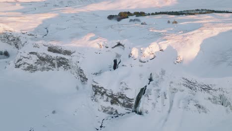 aerial panoramic view of a winter landscape covered in snow, over skogafoss waterfall, in iceland, at sunset