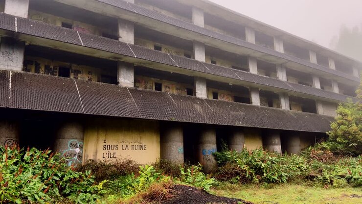 Estructura de hotel de hormigón abandonada con grafitis en la niebla, São Miguel, Azores.