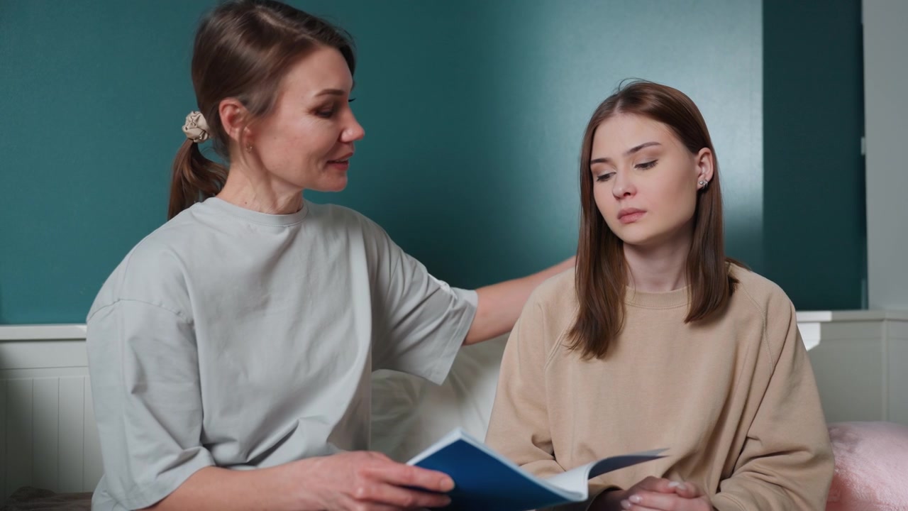 Sessione di tutoraggio in camera da letto a casa, ragazza adolescente che legge un quaderno di grammatica recensito da un tutor dalla voce calma, coaching paziente, interazione di supporto ravvicinata sul letto con parete verde acqua, cuscini accoglienti, studio concentrato