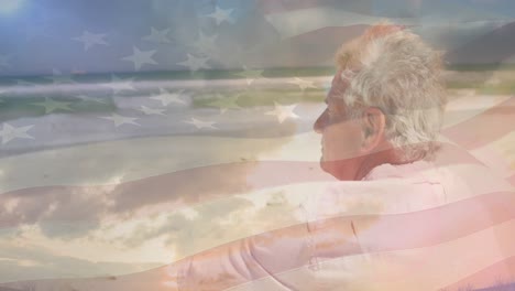 animación de un hombre caucásico sénior sentado en la playa sobre la bandera de los estados unidos de américa