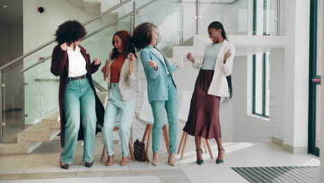 four women having fun dancing in an office setting.