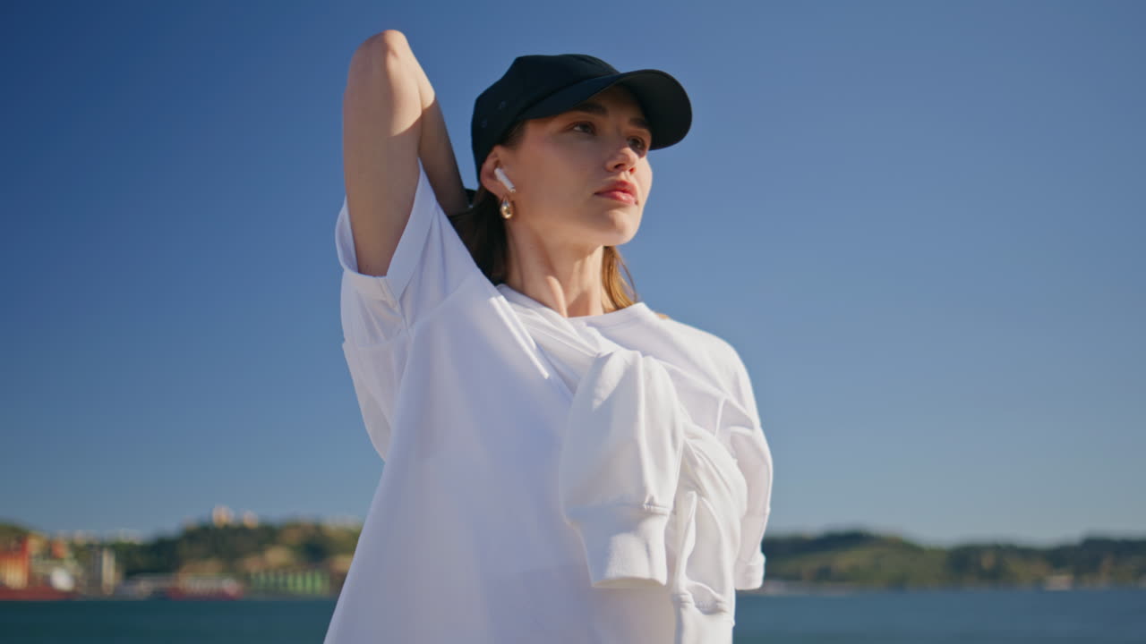 Fit girl warming muscles at morning sport training on quay closeup. Young woman