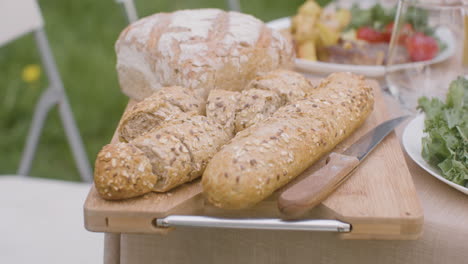 close up shot of fresh bread on a wooden board on a dining table for an outdoor party in the park