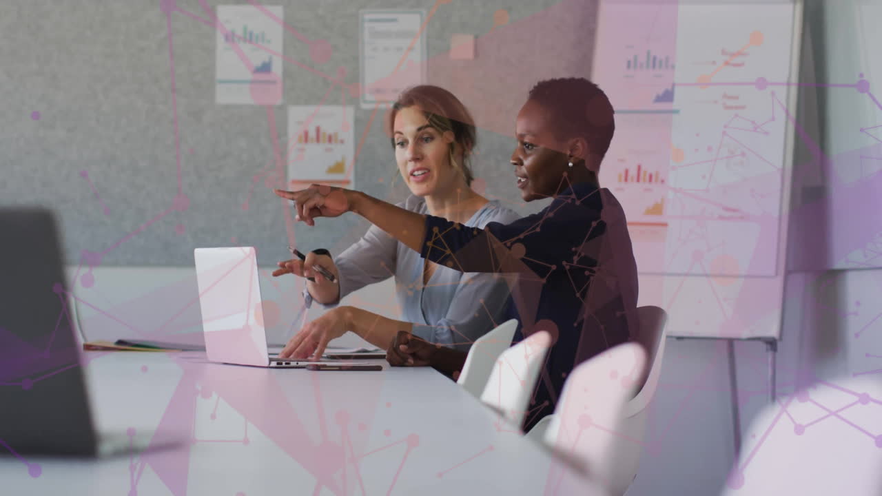 Discussing work with data visualization overlay, two women in office setting