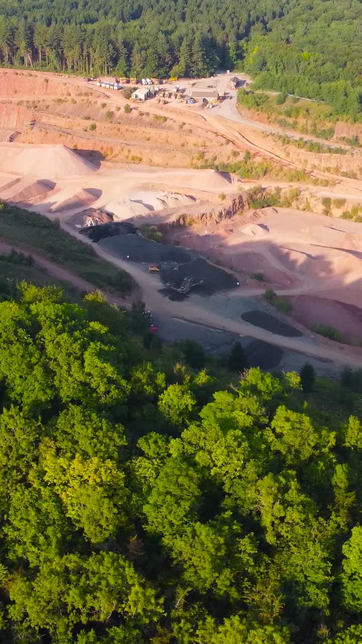 Vertical Video of Sideways Moving Aerial View Over Massive Quarry with Piles of Crushed Aggregates Including Sand Stone Gravel for Use in Road Building and Construction Industry