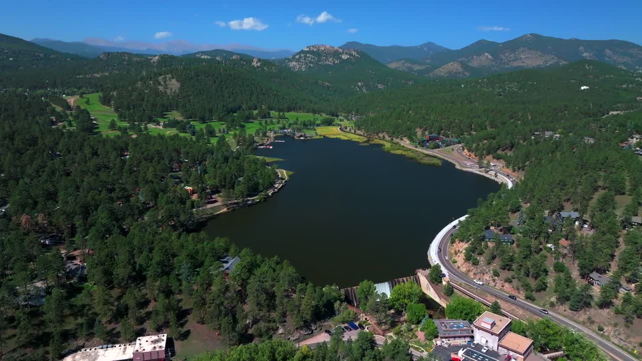 Evergreen Lake House waterfall dam Park and Rec Center Golf Course Keys on the green downtown mountain town summer sunny blue sky flag water dam Colorado aerial drone forward pan up motion