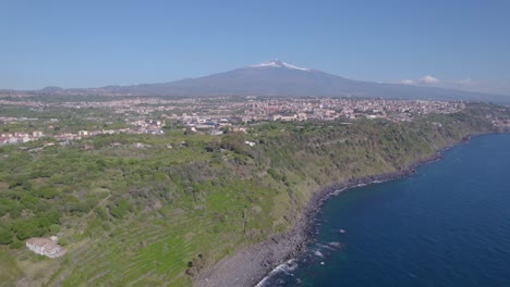 aerial shot of mediterranean sea volcanic cliff near catania, sicily, italy, with mount etna view