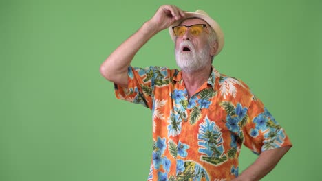 hombre turista barbudo y guapo listo para las vacaciones contra un fondo verde