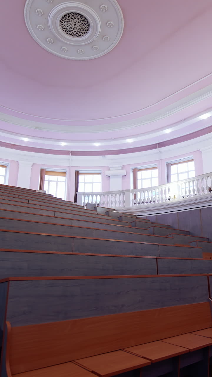 Empty classroom at the university. Modern conference hall with rows of wooden tables. Interior of empty lecture room with purple ceiling. Vertical video