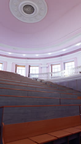 empty classroom at the university. modern conference hall with rows of wooden tables. interior of empty lecture room with purple ceiling. vertical video