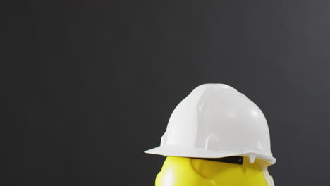 Video-of-close-up-of-colourful-building-helmets-on-gray-background