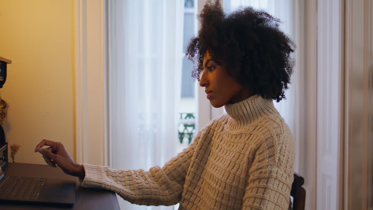 Primo piano di una donna nervosa che guarda lo schermo del computer a casa. Ragazza africana che aspetta una risposta.
