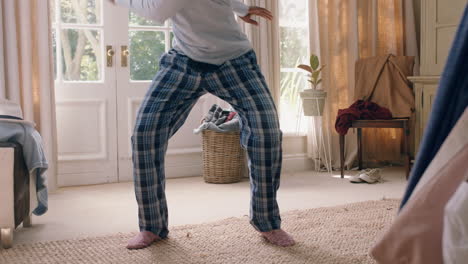 funny african american man dancing in bedroom having fun celebrating feeling positive enjoying successful lifestyle doing silly dance at home on weekend morning wearing pajamas