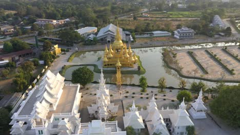 aerial drone of wat rong khun the giant buddhist white temple and golden temple with mountains and scenic landscape in chiang rai, thailand