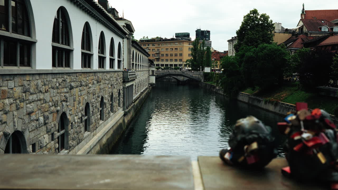 View of the Ljubljanica River with Butchers’ Bridge in the foreground, Triple Bridge in the distance, and Plečnik’s iconic riverside market building on the left in Ljubljana, Slovenia.