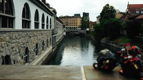 view of the ljubljanica river with butchers’ bridge in the foreground, triple bridge in the distance, and plečnik’s iconic riverside market building on the left in ljubljana, slovenia.