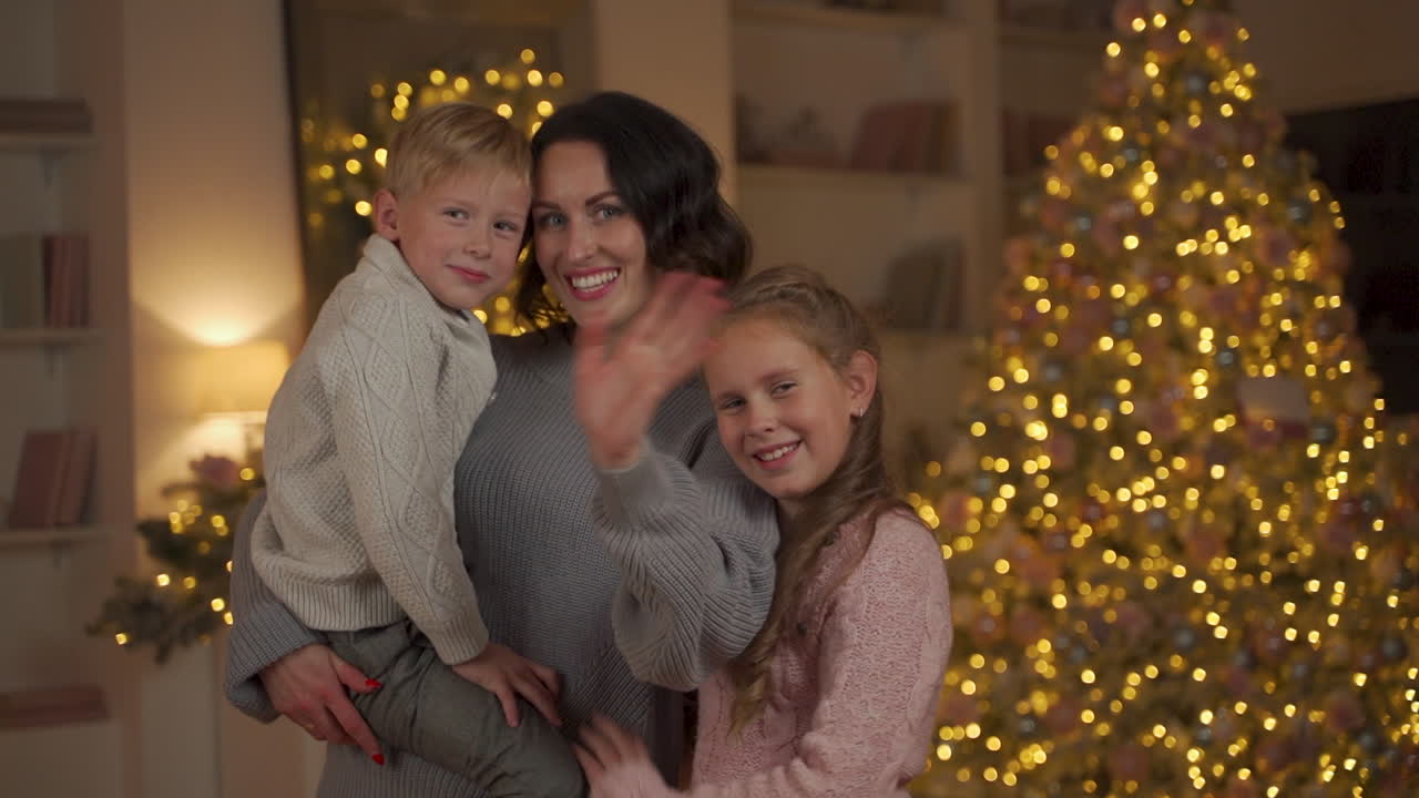 Mother, Little Boy And Girl Pose And Say Hello On Christmas Looking To The Camera