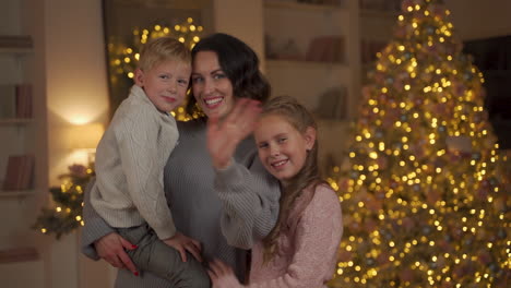 mother, little boy and girl pose and say hello on christmas looking to the camera