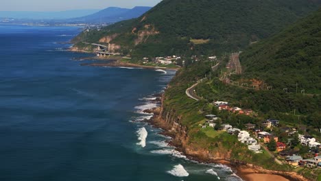 cielo azul soleado mañana de día mar acantilado puente stanwell parque playa cumbres de la colina calva tele drone aéreo wollongong nsw australia sydney costa sur illawarra coalcliff garganta tren coches hacia adelante pan