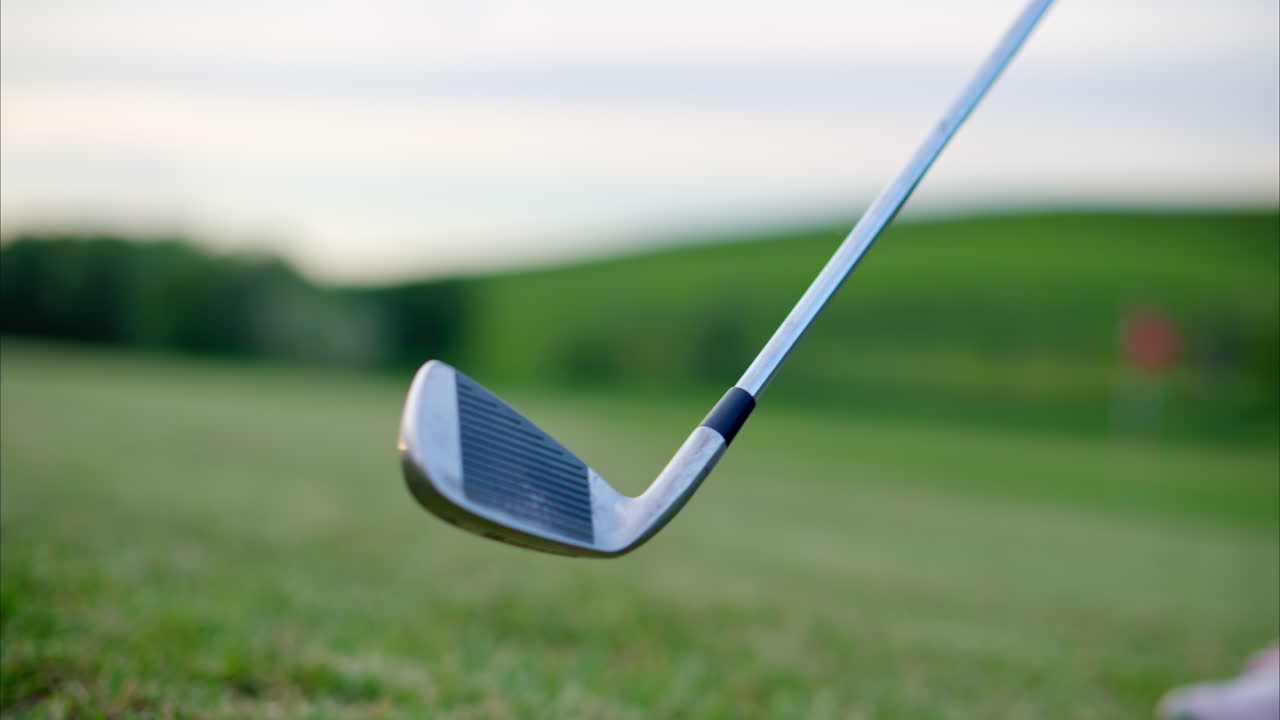 Golf club swinging back and forth on a grass field on a sunny day